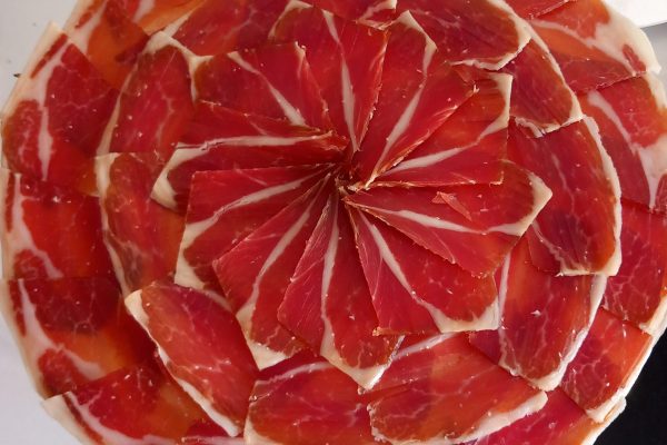 Un experto cortador de jamón ibérico realizando un corte preciso en un evento en Málaga.